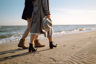 Deniz kenarında yürüyen ve kucaklaşan genç bir çift. Birlikte eğleniyoruz. Moda, yaşam tarzı ve sonbahar havası.