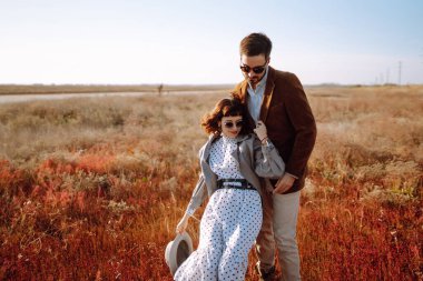 Sonbahar tarlasında yürüyen ve kucaklaşan genç bir çift. Birlikte eğleniyoruz. Moda, yaşam tarzı ve sonbahar havası.