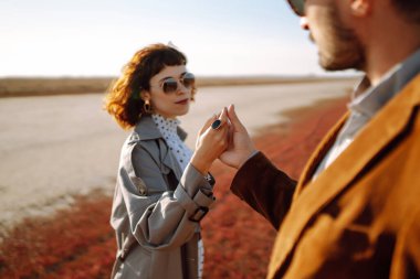 Sonbahar tarlasında yürüyen ve kucaklaşan genç bir çift. Birlikte eğleniyoruz. Moda, yaşam tarzı ve sonbahar havası.