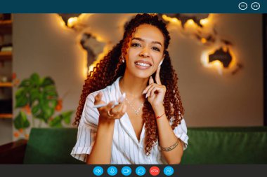 Kafede oturan ve dizüstü bilgisayarında video görüşmesi yapan Afro-Amerikan bir kadının portre portresi. İş kadını müşterisiyle Webcam konferansında konuşuyor. 