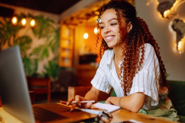 Genç Afro-Amerikalı kadın internette çalışıyor ya da restoranda dizüstü bilgisayarda çalışıyor. Ofis dışında çalışan çekici bir kadın serbest yazar kafeteryada sosyal medyada geziniyor. İş, günlük tutma kavramı