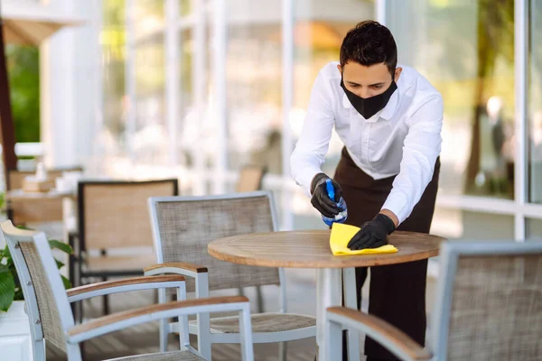 Camarero Mascarilla Protectora Guantes Limpiando Mesa Con Spray Desinfectante Restaurante — Foto de Stock