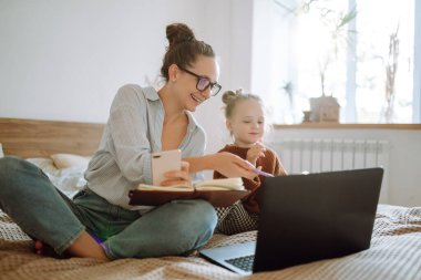 Mutlu anne bebeğiyle ilgilenirken uzaktan bilgisayarla çalışıyor. Koronavirüs salgını sırasında karantina ve kapalı çocuk yuvaları. Doğum izninde çalış. Covid 19.