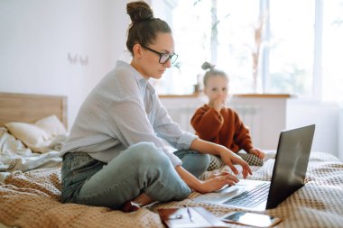 Mutlu anne bebeğiyle ilgilenirken uzaktan bilgisayarla çalışıyor. Koronavirüs salgını sırasında karantina ve kapalı çocuk yuvaları. Doğum izninde çalış. Covid 19.