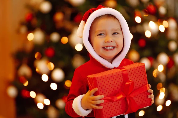 Sorrindo Criança Engraçada Traje Papai Noel Mantém Natal Presente Nas — Fotografia de Stock