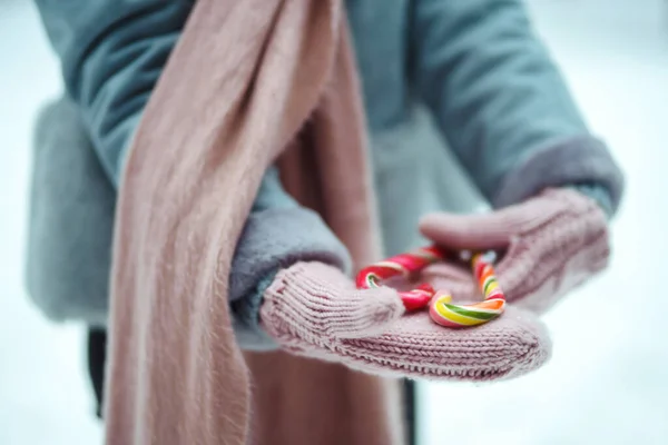 Woman holds in hands Christmas candy cane. Sweet and cute surprise. Young woman with Christmas candy. Celebration winter event. New Year party, Christmas.