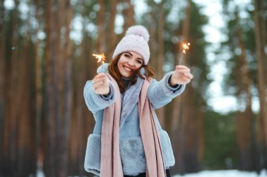 Elinde maytap olan güzel bir kadın. Gülümseyen kadın kış anlarından zevk alıyor. Noel, yeni yıl. Kış yaşam tarzı.