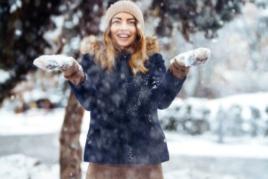 Kış tatillerinde karla oynayan bir kadın, havaya beyaz kar fırlatır. Genç bir kadın kış havasının tadını çıkarıyor. Noel, Yeni Yıl.