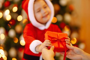 Bir çocuğun elinde Noel hediyesi. Küçük şirin çocuk ailesinden Noel hediyesi alıyor. Kış tatili, yeni yıl.