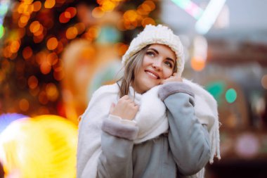 Kış kıyafetleri içinde gülümseyen kadın sokak pazarında poz veriyor. Genç bir kadın kış anlarından zevk alıyor. Noel festivali, kış tatili konsepti..