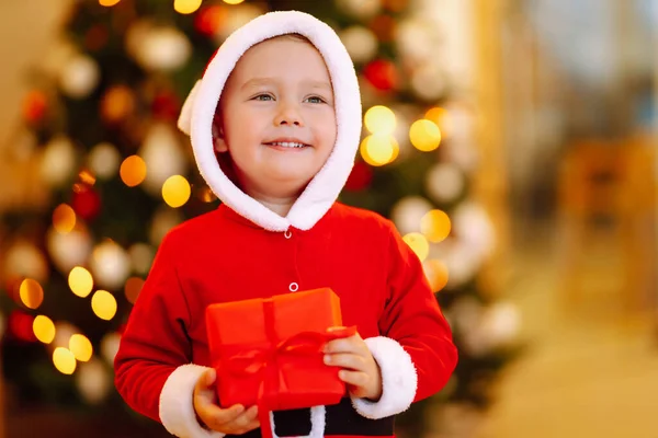 Kleiner Junge Weihnachtsmannkostüm Mit Weihnachtsgeschenk Glückliches Kind Mit Roter Geschenkschachtel — Stockfoto