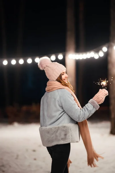 クリスマスは手に輝きます 冬の森で輝きを持つ陽気な若い女性 お祭りのガーランドライト クリスマス — ストック写真