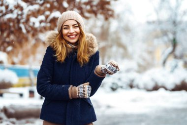Karlı ormanda güzel bir kadın. Kışlık elbiseli genç bayan parkta neşe içinde poz veriyor. Kış tatili, Noel, Yeni Yıl.