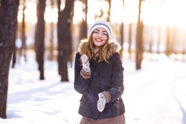 Kış tatilin kutlu olsun. Karlı ormanda karla oynayan tatlı bir kadın. Kışlık elbiseli genç bayan kışın tadını çıkarıyor. Kış tatili.