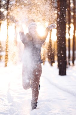 Kış tatilin kutlu olsun. Karlı ormanda karla oynayan tatlı bir kadın. Kışlık elbiseli genç bayan kışın tadını çıkarıyor. Kış tatili.