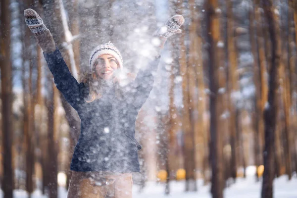 Kış tatilin kutlu olsun. Karlı ormanda karla oynayan tatlı bir kadın. Kışlık elbiseli genç bayan kışın tadını çıkarıyor. Kış tatili.