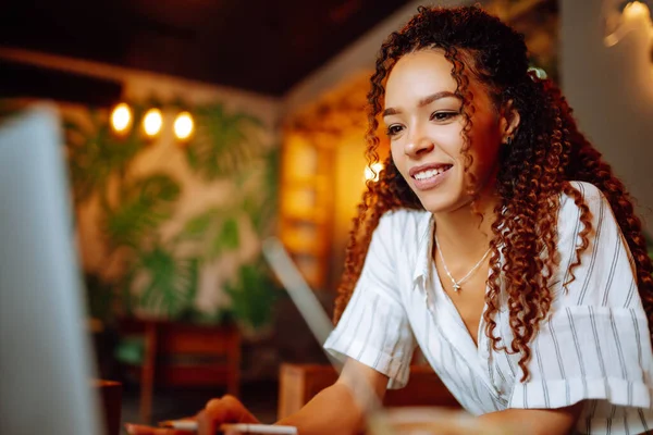 여성이 카페에서 노트북 컴퓨터로 일하고 있습니다 미소짓는 학생들은 온라인으로 헤드폰 — 스톡 사진