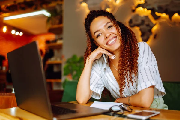 여성이 카페에서 노트북 컴퓨터로 일하고 있습니다 미소짓는 학생들은 온라인으로 헤드폰 — 스톡 사진