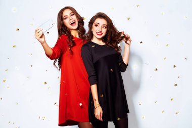 Selfie zamanı. İki Noel genç bayanı beyaz arka planda poz vererek selfie çekiyor. Mutlu parti anları. Kış tatili.
