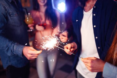 Noel 'in ışıltısı ellerde. Kutlama sırasında ellerinde maytap olan genç ve mutlu bir kalabalık. Bengal ateşlerinin ışıltılı ışıkları 2021.