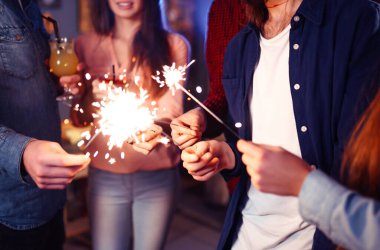 Noel 'in ışıltısı ellerde. Kutlama sırasında ellerinde maytap olan genç ve mutlu bir kalabalık. Bengal ateşlerinin ışıltılı ışıkları 2021.