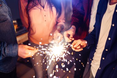 Noel 'in ışıltısı ellerde. Kutlama sırasında ellerinde maytap olan genç ve mutlu bir kalabalık. Bengal ateşlerinin ışıltılı ışıkları 2021.