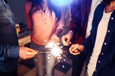 Noel 'in ışıltısı ellerde. Kutlama sırasında ellerinde maytap olan genç ve mutlu bir kalabalık. Bengal ateşlerinin ışıltılı ışıkları 2021.