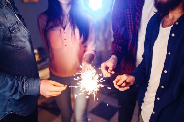 Noel 'in ışıltısı ellerde. Kutlama sırasında ellerinde maytap olan genç ve mutlu bir kalabalık. Bengal ateşlerinin ışıltılı ışıkları 2021.