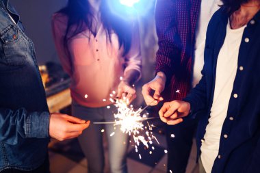 Noel 'in ışıltısı ellerde. Kutlama sırasında ellerinde maytap olan genç ve mutlu bir kalabalık. Bengal ateşlerinin ışıltılı ışıkları 2021.