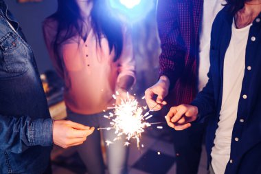 Noel 'in ışıltısı ellerde. Kutlama sırasında ellerinde maytap olan genç ve mutlu bir kalabalık. Bengal ateşlerinin ışıltılı ışıkları 2021.