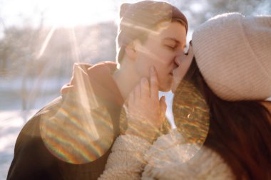 Mutlu çift kış parkında sarılıp öpüşüyor. Genç adam ve kadın kar ormanlarında eğleniyorlar. Tatiller, mevsimler, aşk ve eğlence kavramı.