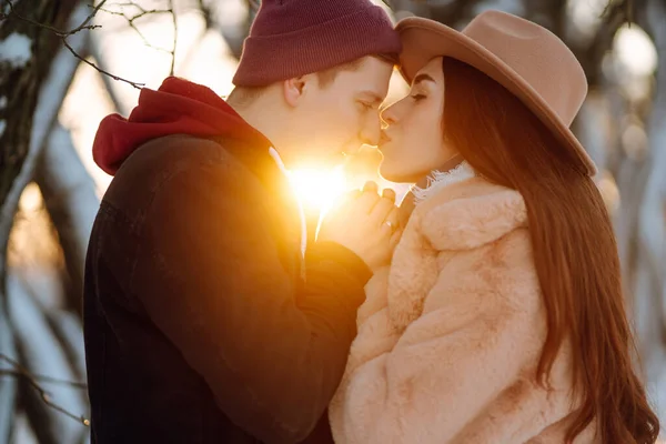 若いカップルは 日没時に冬に屋外で抱き合って笑っています 幸せな男と女は雪の森の中でお互いを楽しむ 愛とレジャーの概念 — ストック写真