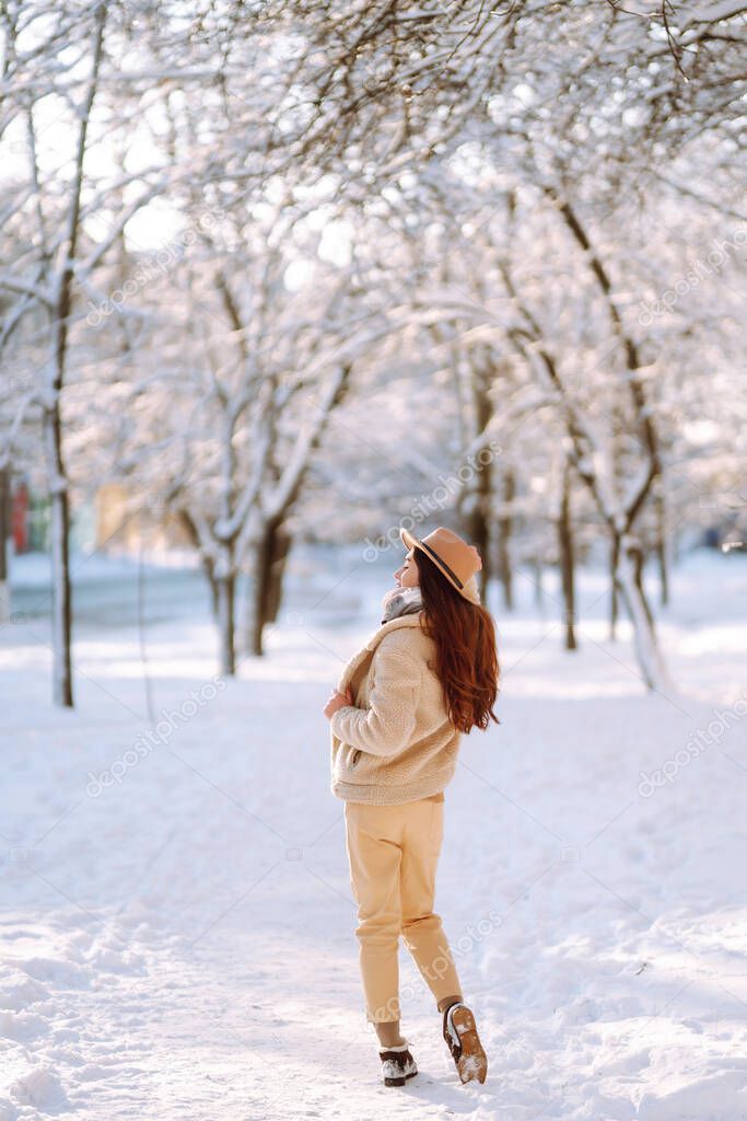 Beautiful  woman enjoys winter, frosty day. Fashion young woman in the snow forest. Holidays, season and leisure concept. Christmas, New year.