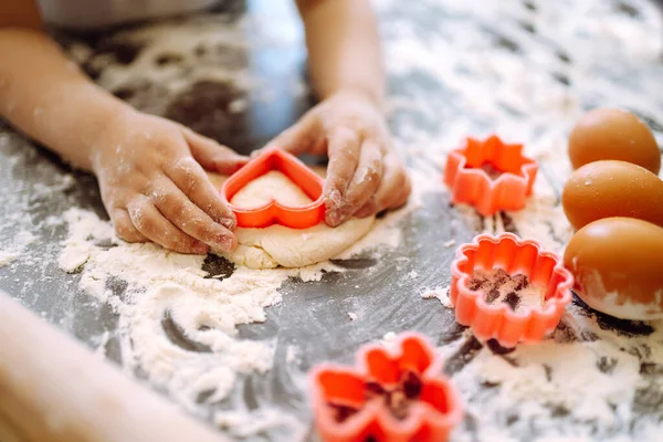 Kids hands cutting out shapes and making cookies. Making biscuits for christmas decorations. Children's art project, a craft for children.