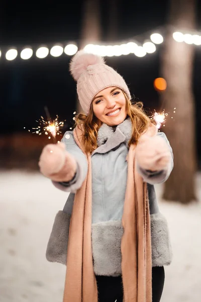 冬の森で輝きを持つ陽気な若い女性 お祭りのガーランドライト クリスマス — ストック写真