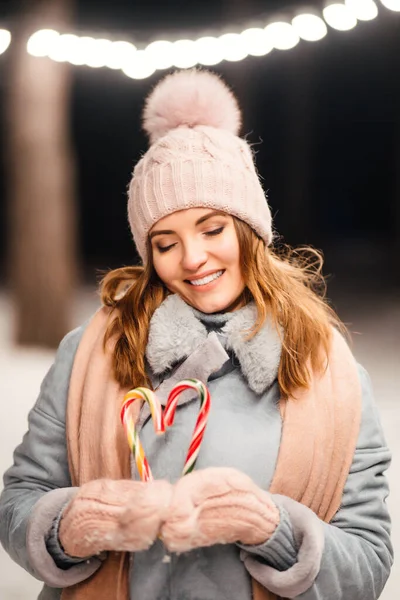 女性の手の中にクリスマスストライプキャンディーの杖 甘くかわいい驚き 甘いキャンディーを持っている若い女性 — ストック写真
