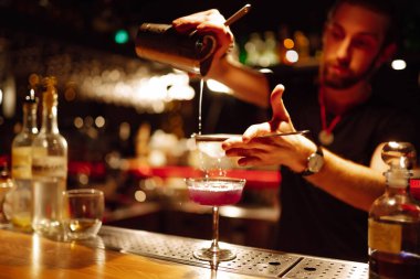 Barmenin yakın plan ayrıntıları bir gece kulübünde kokteyl yapar. Profesyonel barmen elek yoluyla bardaktan bardağa kadar karıştırıyor. Parti, kutlama, içki, tatil.