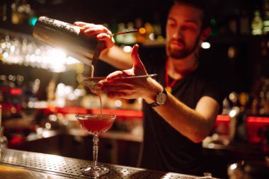 Barmenin yakın plan ayrıntıları bir gece kulübünde kokteyl yapar. Profesyonel barmen elek yoluyla bardaktan bardağa kadar karıştırıyor. Parti, kutlama, içki, tatil.