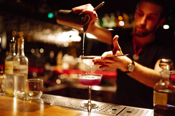 Barmenin yakın plan ayrıntıları bir gece kulübünde kokteyl yapar. Profesyonel barmen elek yoluyla bardaktan bardağa kadar karıştırıyor. Parti, kutlama, içki, tatil.