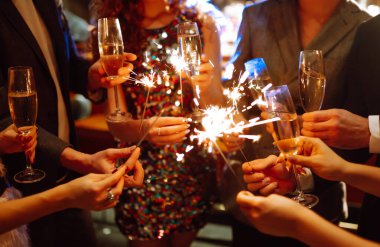 Elinde maytaplar var. Bir grup mutlu insan partide maytap tutuyor. Genç arkadaşlar bir gece kulübünde şampanya bardaklarını tokuşturuyorlar. Kutlama, insanlar ve tatil kavramı.