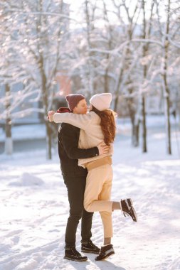 Sevgi dolu bir çift kar ormanında sarılıp öpüşüyor. Birlikte eğleniyoruz. Gençlik, aşk ve yaşam tarzı kavramı. Kış tatili.