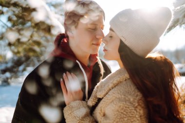 Sevgi dolu bir çift kar ormanında sarılıp öpüşüyor. Birlikte eğleniyoruz. Gençlik, aşk ve yaşam tarzı kavramı. Kış tatili.