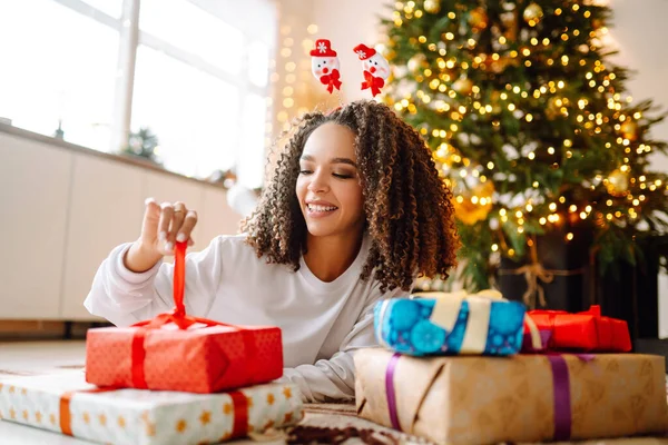 Ευτυχισμένη Γυναίκα Ανοίγει Δώρα Κοντά Στο Χριστουγεννιάτικο Δέντρο Νεαρή Σγουρή — Φωτογραφία Αρχείου