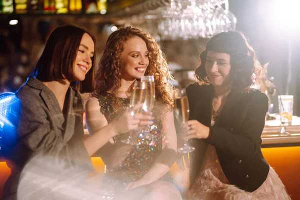 Three young Woman with champagne glasses at night club.  Women friends drinking champagne  in the bar. Party, celebration, friends, bachelorette party, birthday, winter holidays concept.