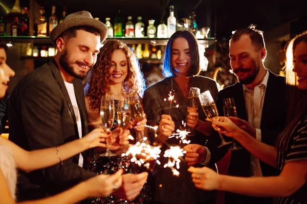 朋友们用火花和香槟庆祝圣诞节或新年 一群快乐的人享受着篝火派对 生活方式的概念 — 图库照片