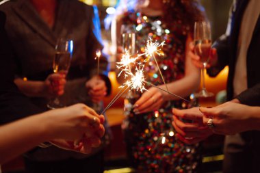 Ellerinde pırıl pırıl parlıyor. Bir grup mutlu insan havai fişeklerle eğleniyor. Kış tatili, gençlik, yaşam tarzı konsepti.