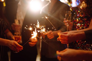 Ellerinde pırıl pırıl parlıyor. Bir grup mutlu insan havai fişeklerle eğleniyor. Kış tatili, gençlik, yaşam tarzı konsepti.