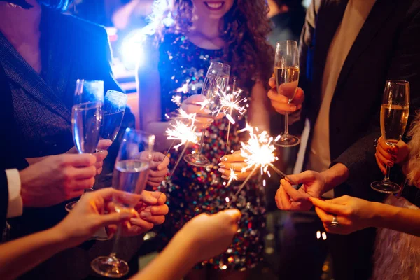 Ellerinde pırıl pırıl parlıyor. Bir grup mutlu insan havai fişeklerle eğleniyor. Kış tatili, gençlik, yaşam tarzı konsepti.