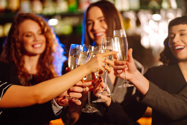 Group of happy people clinking glasses of champagne at party. Young friends celebrating winter holiday together with champagne. Party, celebration, drink, birthday concept.