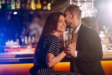 Barda içki içmekten zevk alan mutlu bir çift. Genç bir adam ve bir kadın cam şampanya tokuşturuyor, kış tatilinin tadını çıkarıyorlar. Parti, kutlama, içki, doğum günü konsepti. Romantik bir akşam.